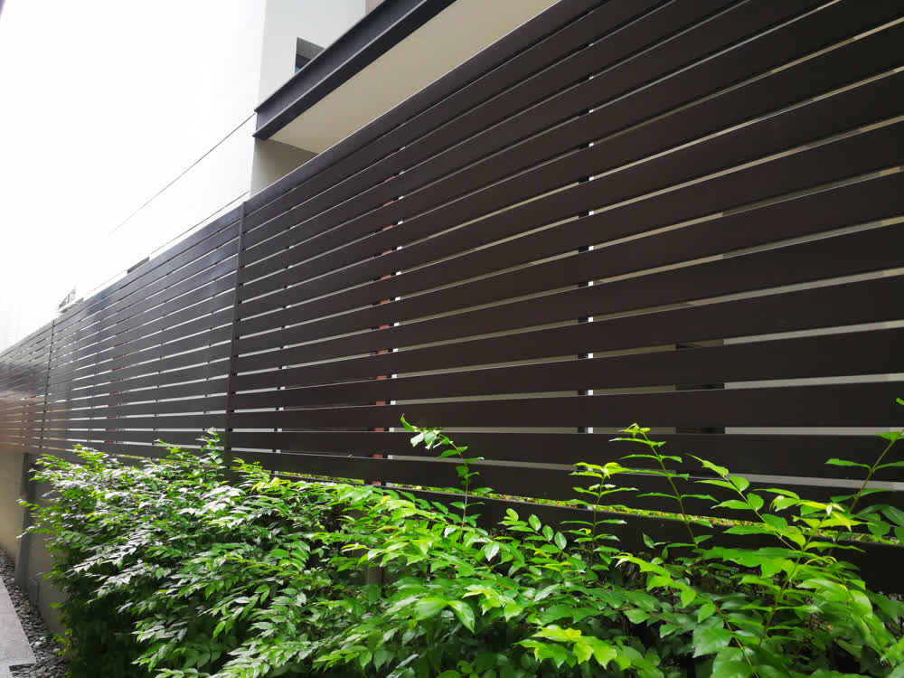 Black horizontal wooden fence with Murraya paniculata planting